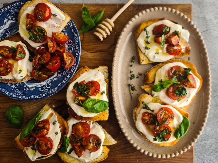 Gezouten bruschetta's met opgeklopte ricotta, gemarineerde tomaten en honing