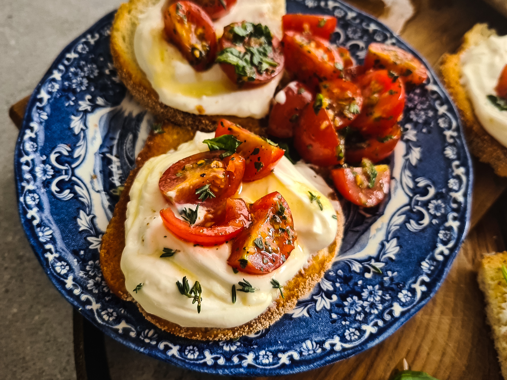 Gezouten bruschetta's met opgeklopte ricotta, gemarineerde tomaten en honing